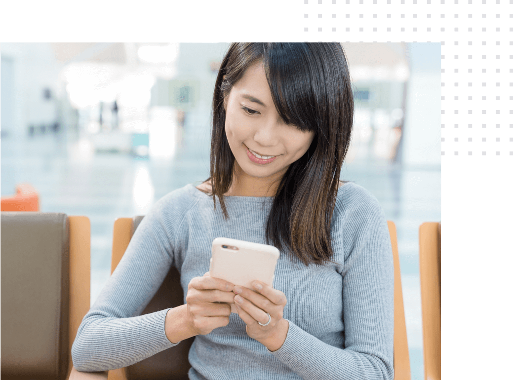 A woman sits with a smartphone and uses a mobile hotel application